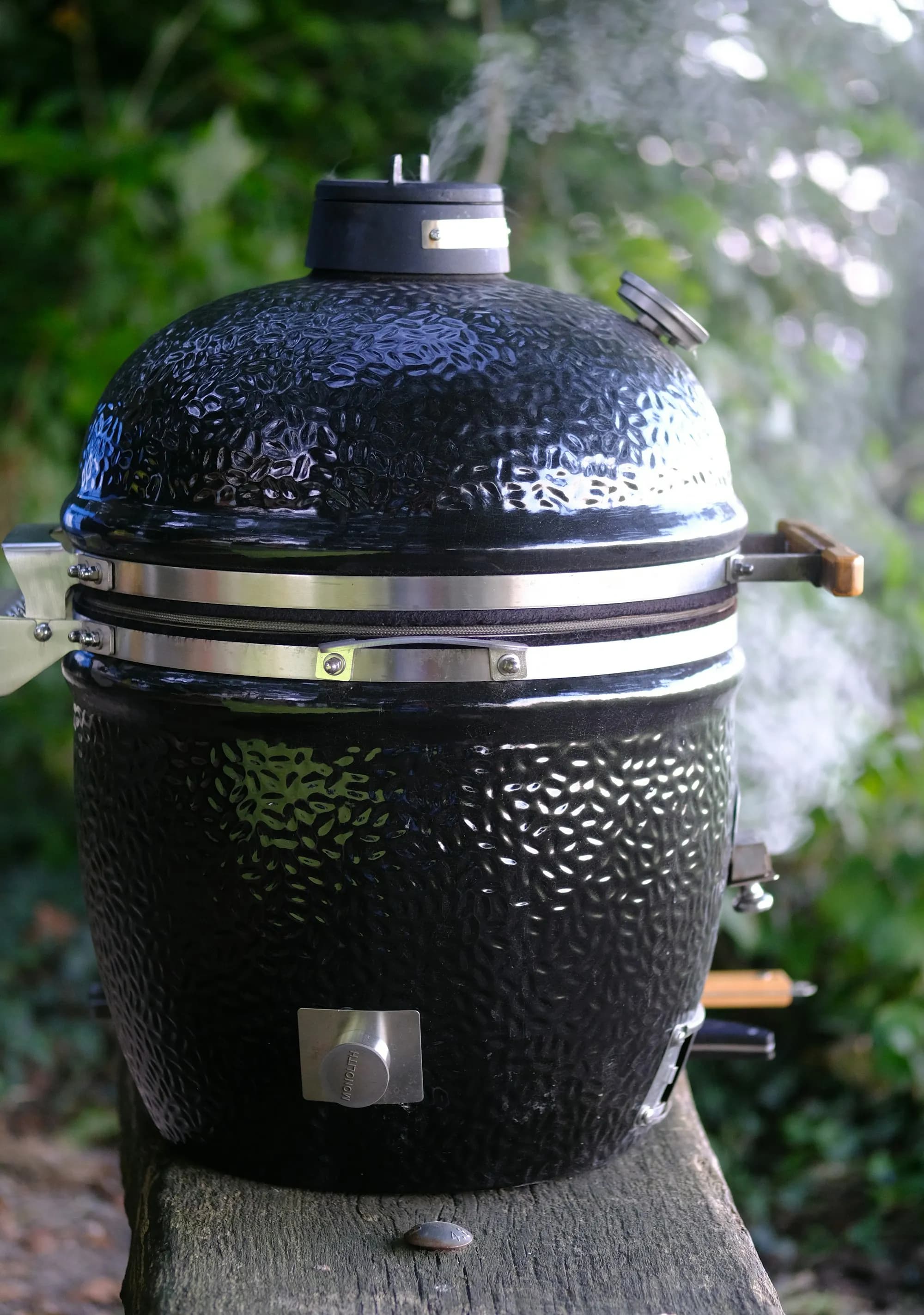 Big Green Egg Large de cerámica verde en una terraza, con la cúpula abierta y las brasas encendidas listas para asar