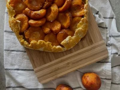 Galette rústica de albaricoques caramelizados con miel, recién horneada sobre tabla de madera, junto a albaricoques frescos.