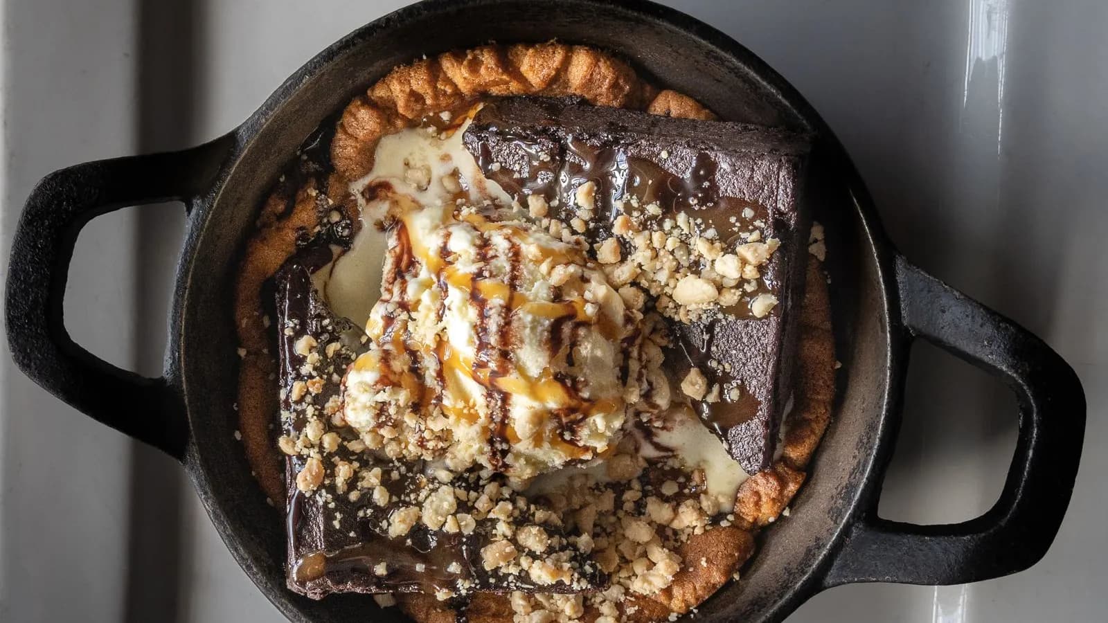 Brownie de chocolate en sartén de hierro con helado y caramelo