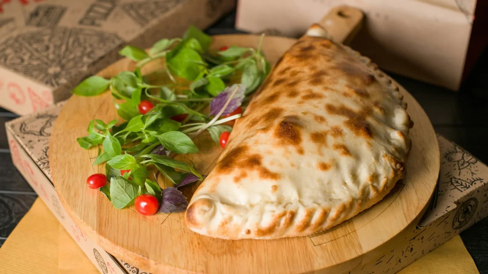 Calzone dorado y sellado sobre tabla de madera con hojas de albahaca