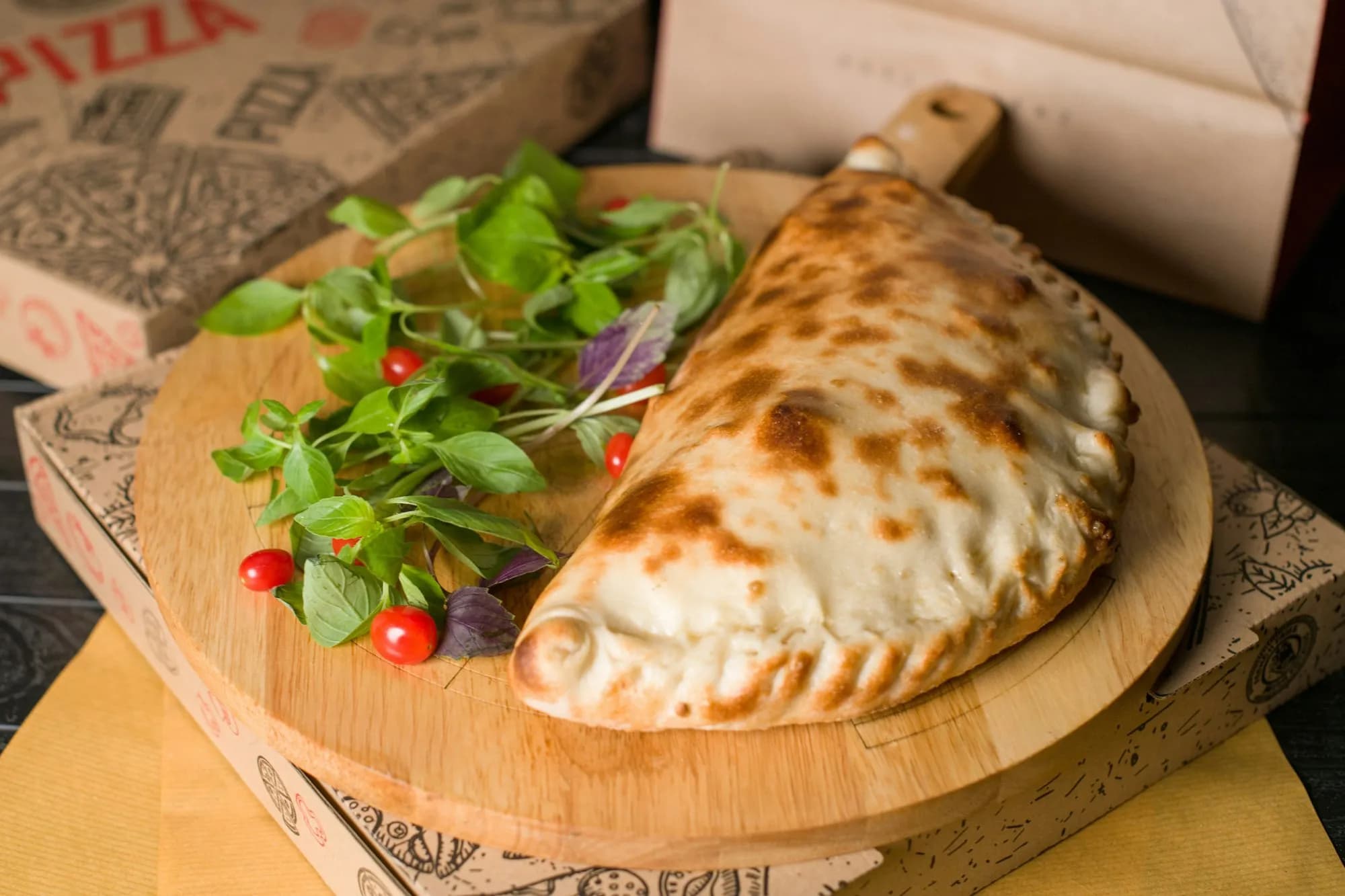 Calzone dorado y sellado sobre tabla de madera con hojas de albahaca
