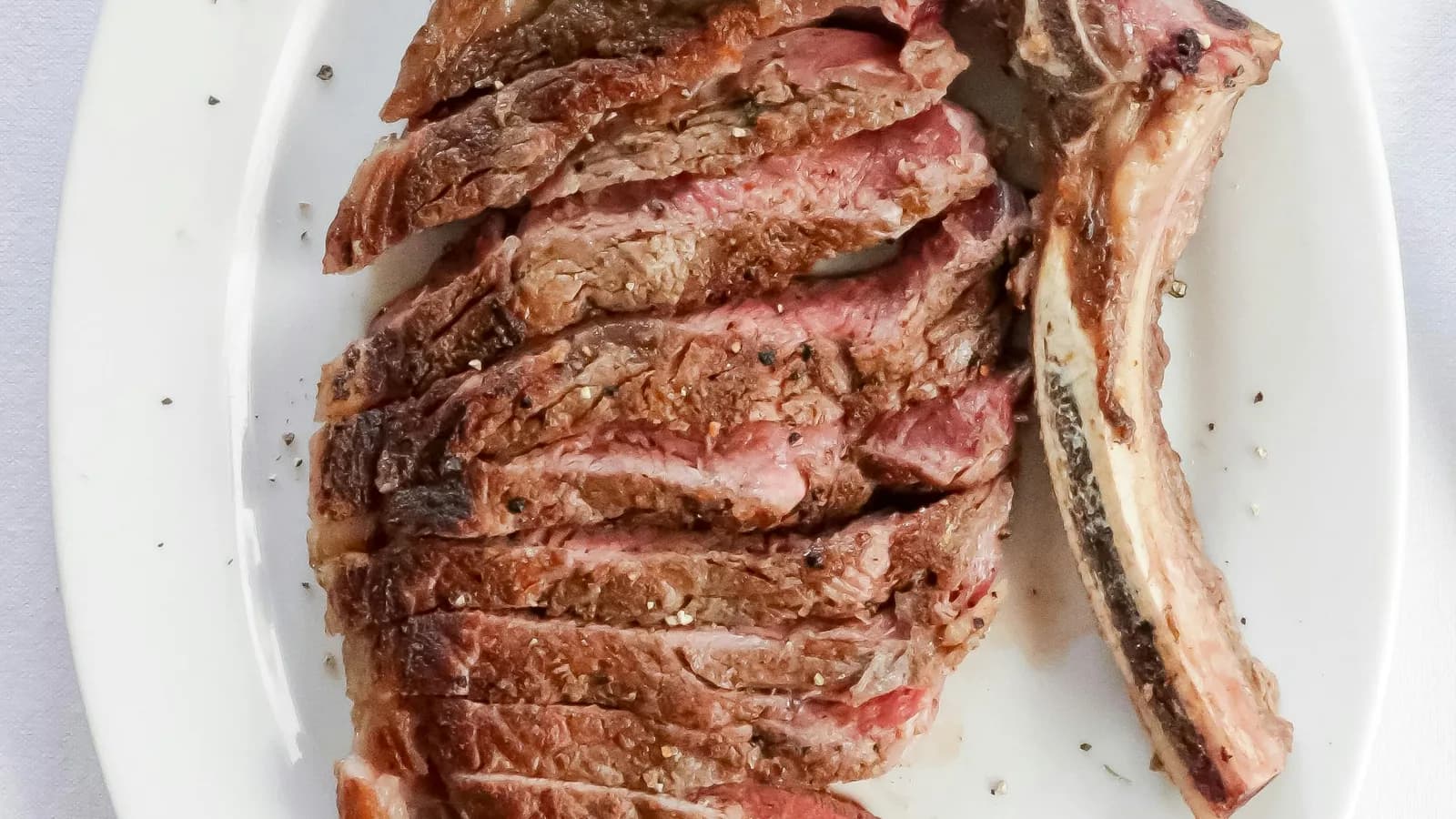 Chuletón a la parrilla recién salido del kamado, costra ennegrecida y carne rosada
