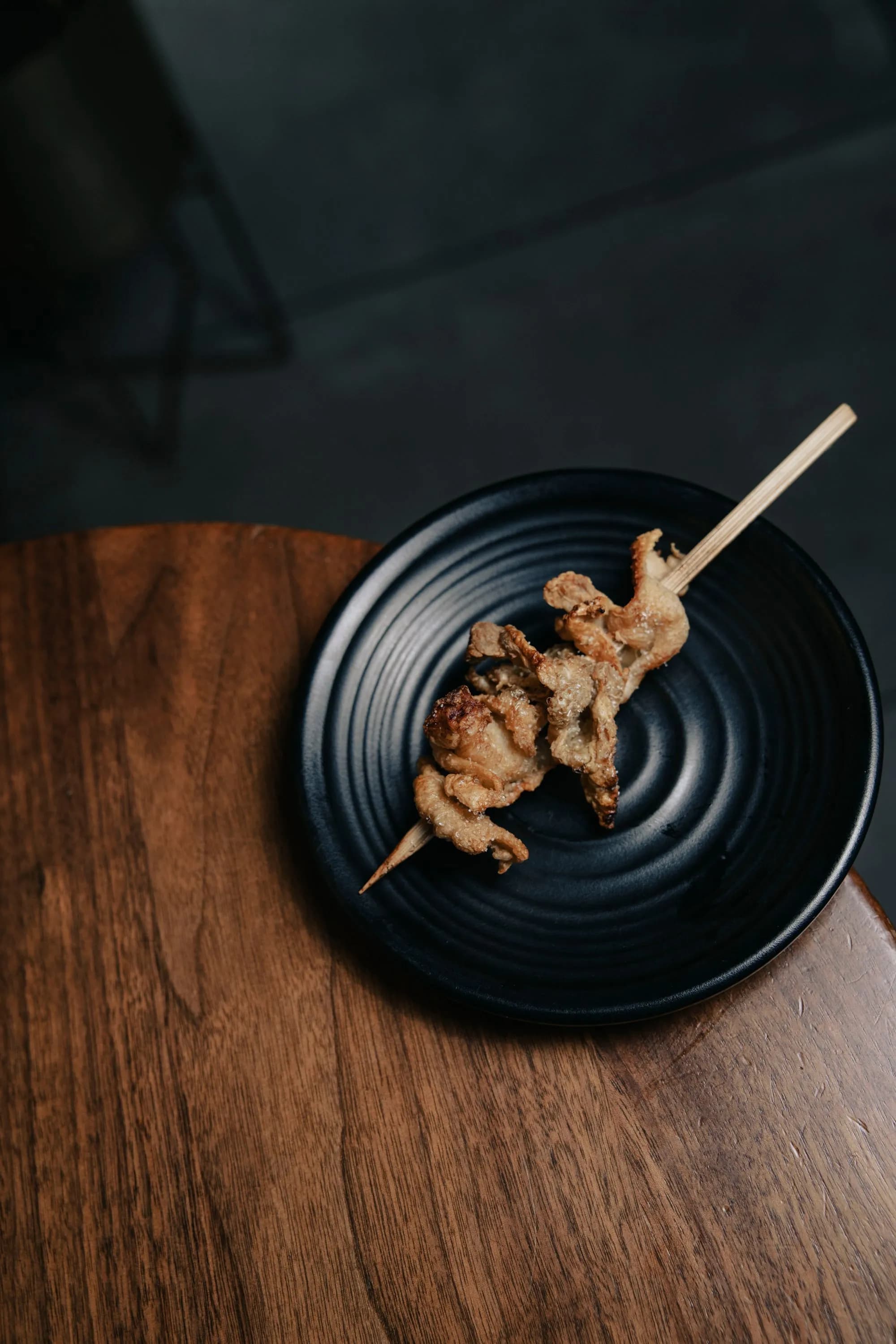 Codornices doradas con glaseado de miel en brocheta, presentadas sobre un plato oscuro, estilo editorial.