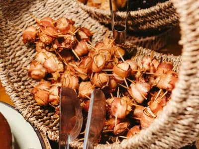 Dátiles Medjool envueltos en bacon caramelizado y glaseados con Pedro Ximénez, recién hechos sobre la parrilla de un kamado.