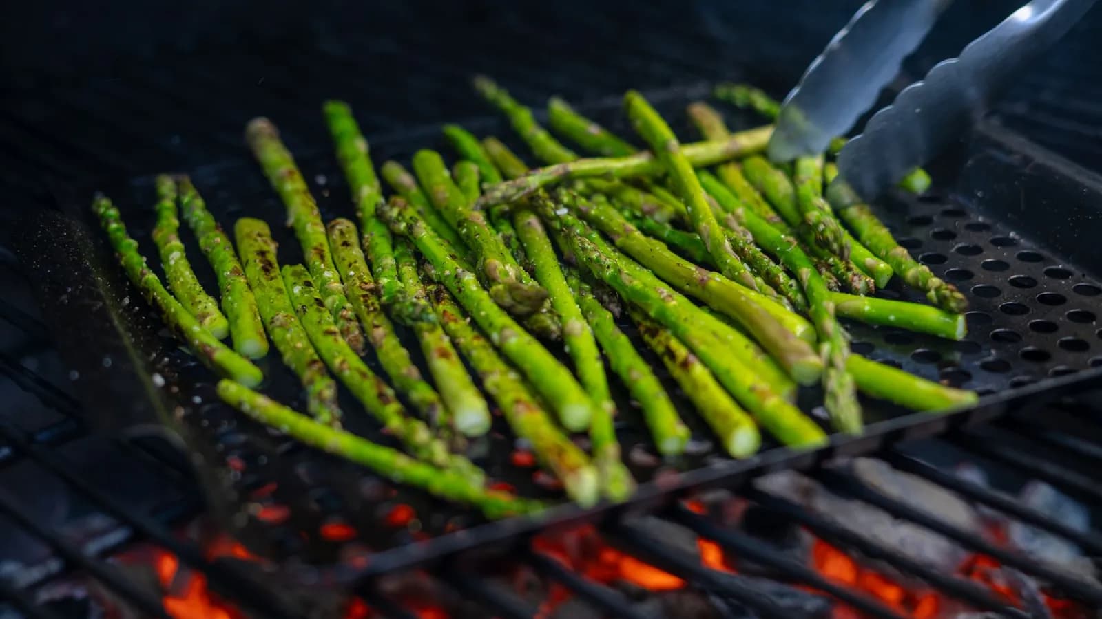 Espárragos trigueros marcados a la brasa sobre la rejilla de un kamado, con ralladura de limón y escamas de sal, algunos envueltos en jamón serrano.