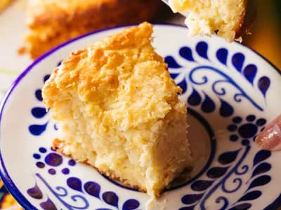 Porción de pan de maíz dorado en un plato de cerámica azul y blanca, con una cuchara cogiendo un trozo