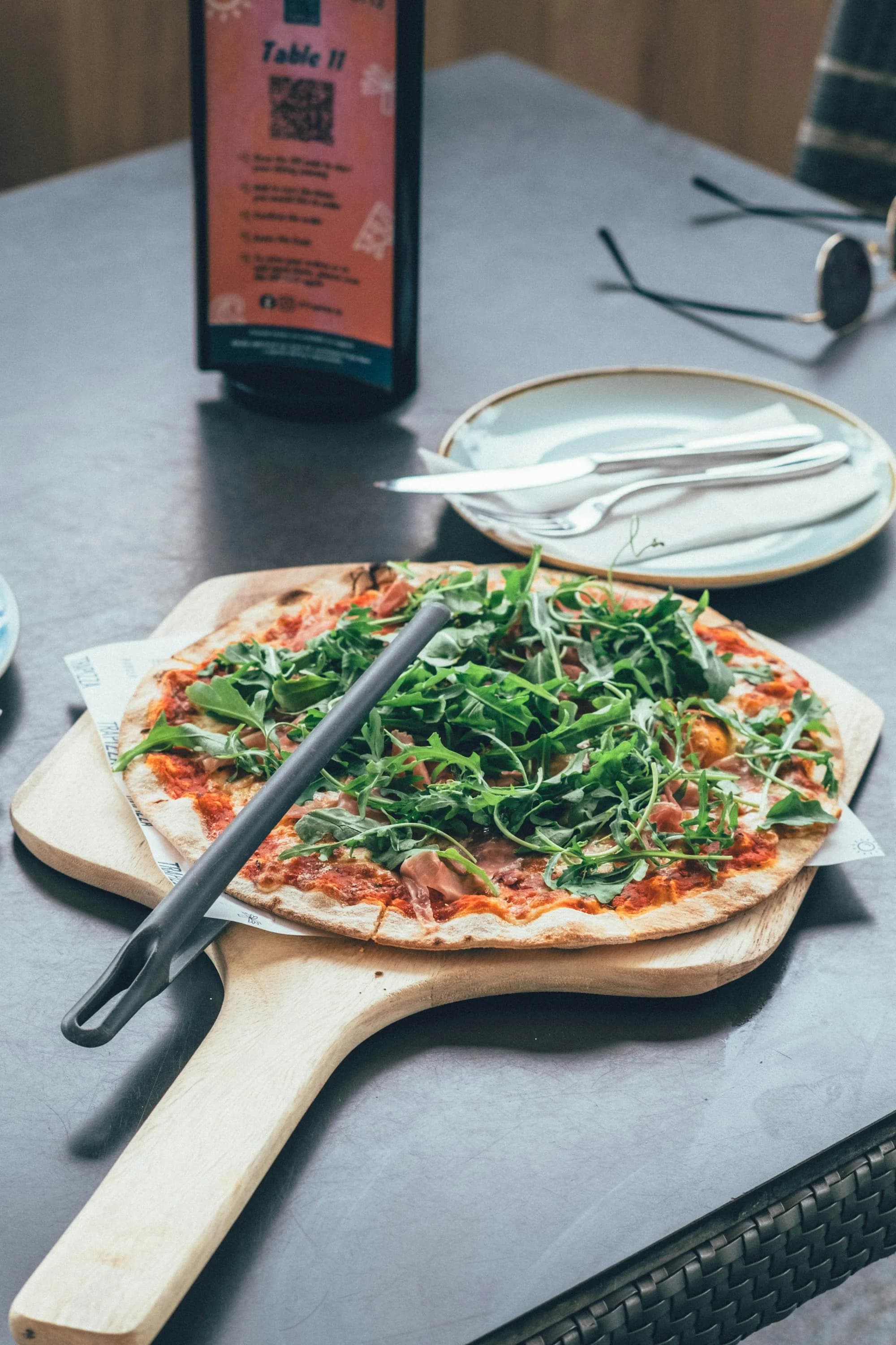 Pizza de jamón y rúcula fresca servida sobre pala de madera