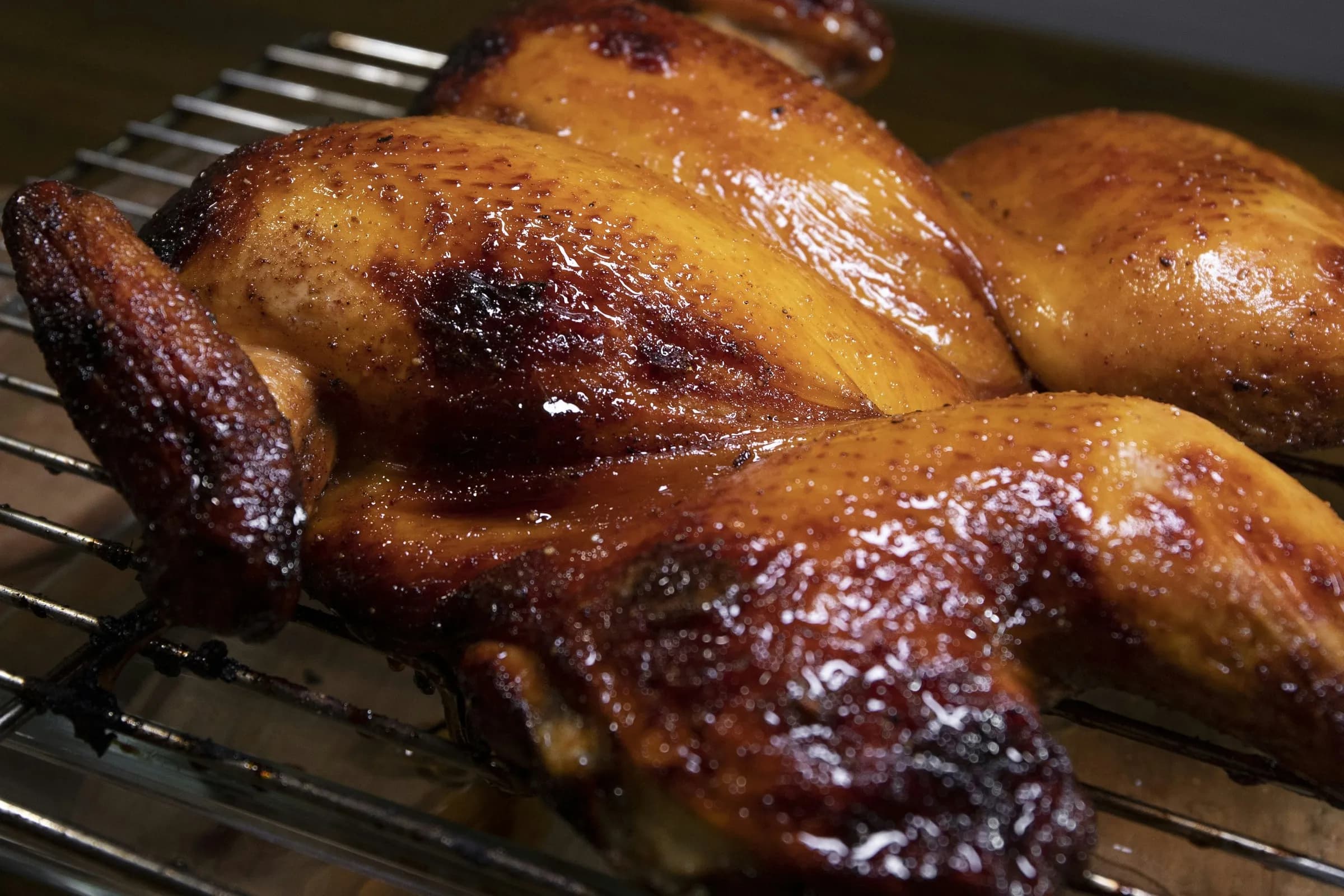 Pollo entero abierto en mariposa (spatchcock) asado al kamado, con la piel dorada y lacada, sobre rejilla de acero