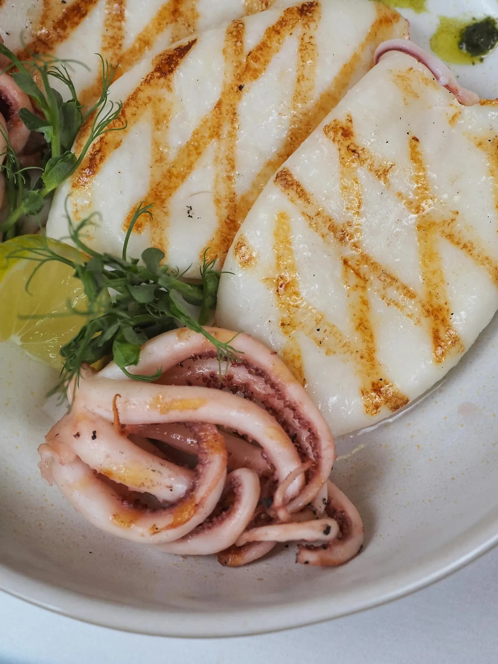 Sepia a la plancha con marcas de parrilla, limón y brotes