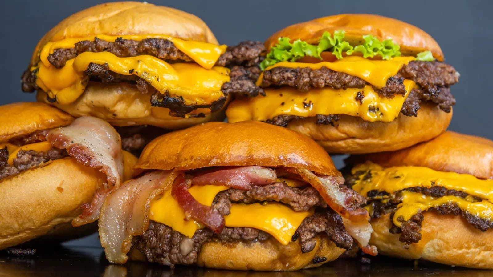 Hamburguesas dobles con queso fundido apiladas, con la carne de bordes tostados