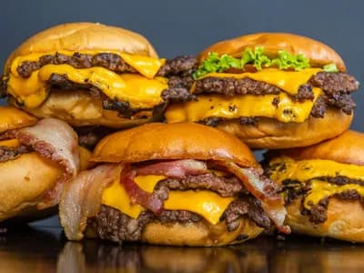 Hamburguesas dobles con queso fundido apiladas, con la carne de bordes tostados