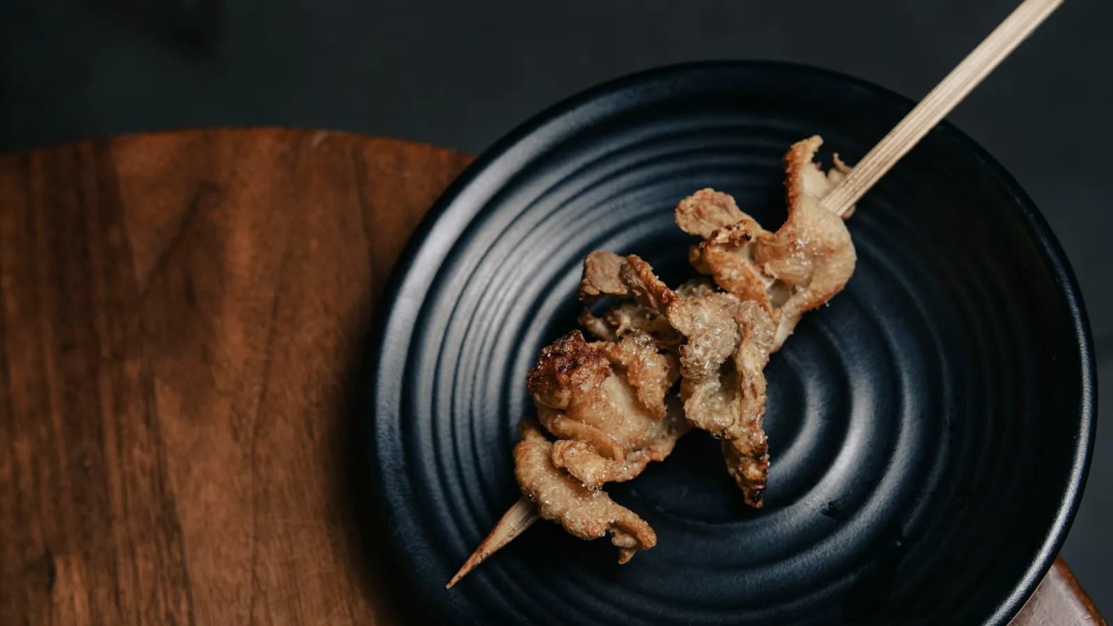 Codornices doradas con glaseado de miel en brocheta, presentadas sobre un plato oscuro, estilo editorial.