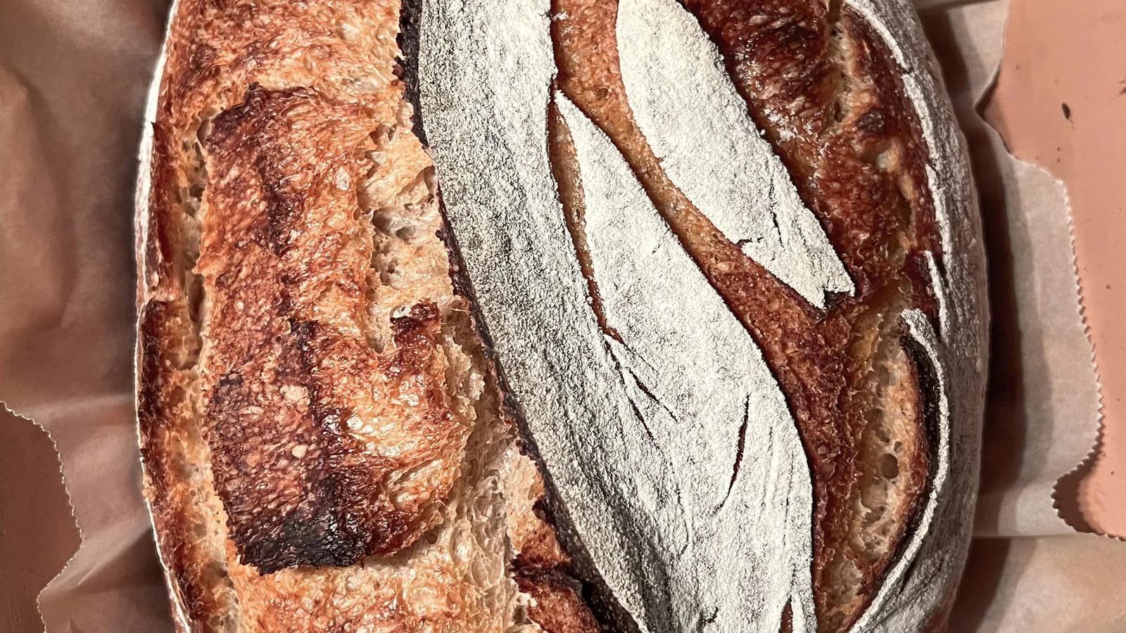 Hogaza de masa madre dorada saliendo de una cocotte de hierro fundido