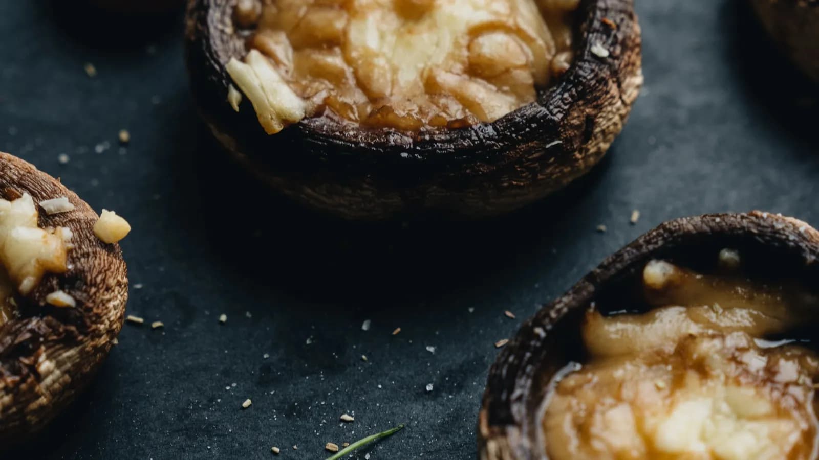 Champiñones Portobello rellenos al ajillo y gratinados con queso fundido y perejil, recién hechos.