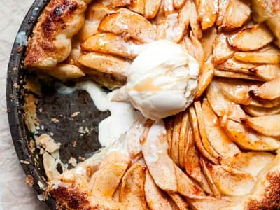 Tarta tatin de manzana caramelizada en molde de hierro, con bola de helado fundiéndose